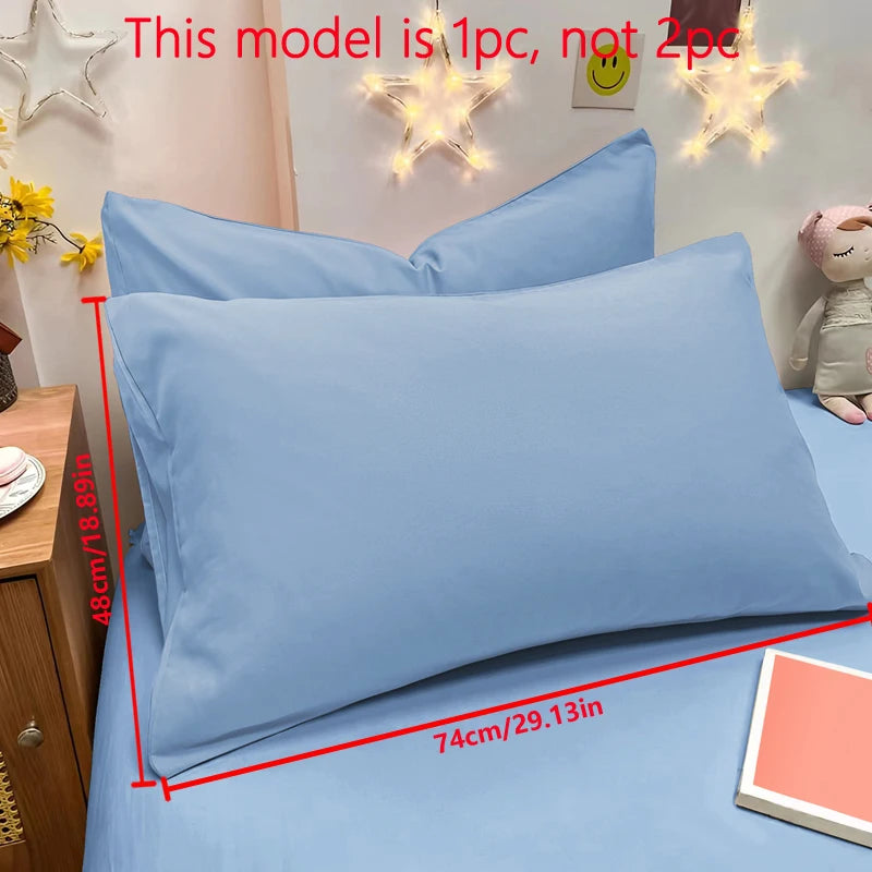 A light blue matte solid color pillowcase is displayed on a bed, with decorative star lights in the background.
