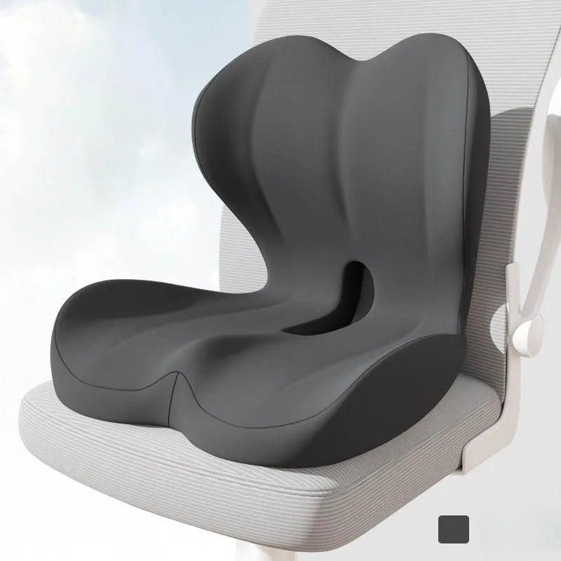 A gray ergonomic memory foam lumbar seat cushion is shown resting on a white chair.