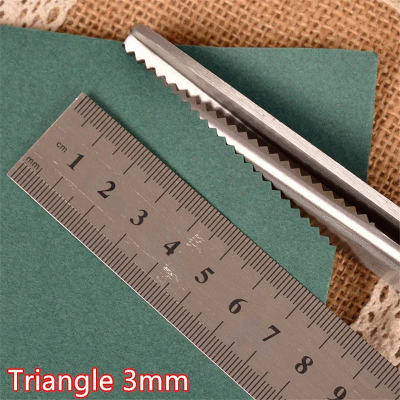 A stainless steel triangle-shaped ruler or measuring tool is shown next to a pair of sewing shears on a green surface.
