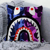A decorative pillow cover featuring a purple and blue print of an aggressive cat face with large eyes and a prominent toothy 