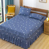 A navy blue fitted bed sheet with a white diamond pattern and lace trim is displayed on a wooden bed.