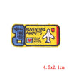 Yellow embroidered iron-on patch featuring the text Adventure Awaits and a white airplane icon.