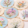 A collection of beginner embroidery kits featuring various floral patterns on light blue and cream fabric.