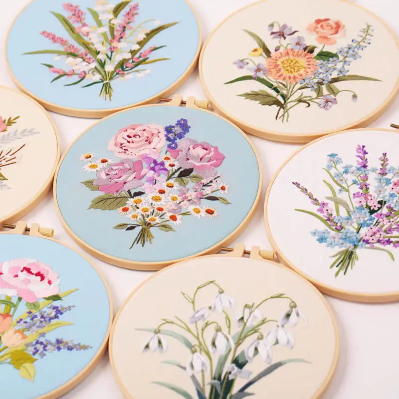 A collection of beginner embroidery kits featuring various floral patterns on light blue and cream fabric.