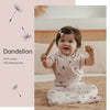 A baby wearing a light pink cotton sleeping bag with a subtle pattern, sitting on a beige blanket.