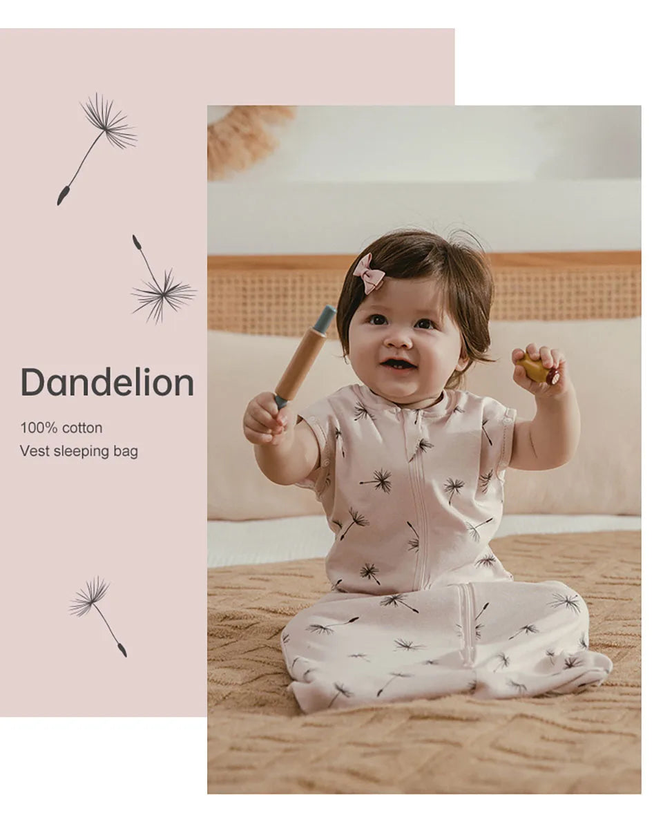 A baby wearing a light pink cotton sleeping bag with a subtle pattern, sitting on a beige blanket.