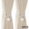 A pair of pearl rope tiebacks with silver cord and round pearl-like beads shown against a light beige fabric background.