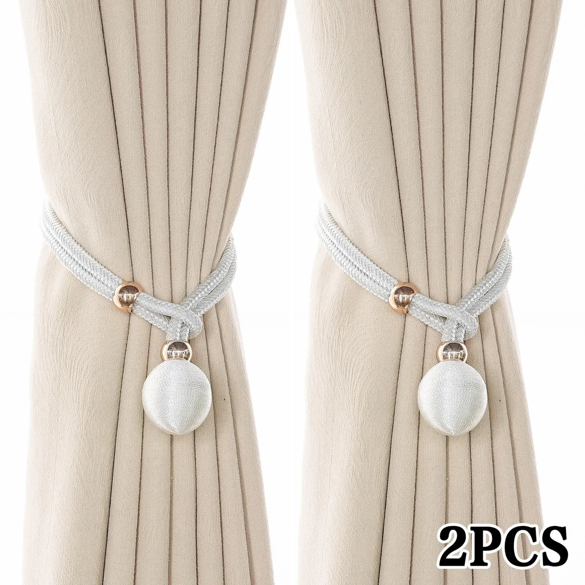 A pair of pearl rope tiebacks with silver cord and round pearl-like beads shown against a light beige fabric background.