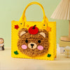 A yellow felt bear-shaped bag with orange handles and red accents for a beginner craft kit.