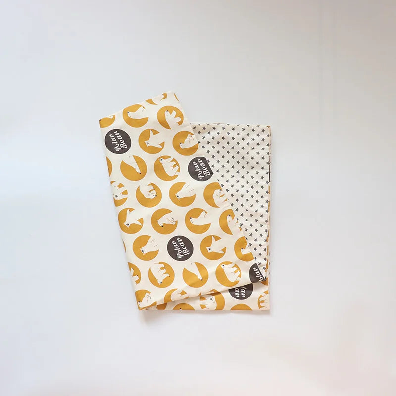 A rolled soft cotton baby pillow cover featuring a pattern of yellow and white elephants on a cream background.