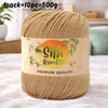 A skein of beige bamboo silk blend yarn is shown on a white surface with a label indicating premium quality.