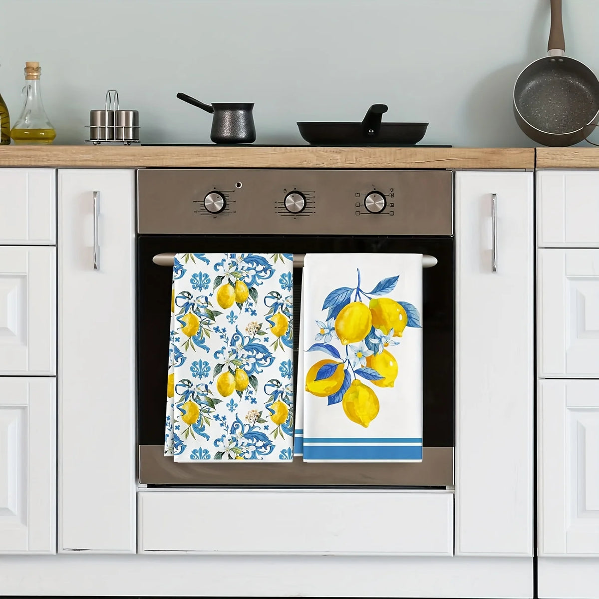 A set of two blue-edged lemon kitchen towels hanging in a built-in oven cabinet.