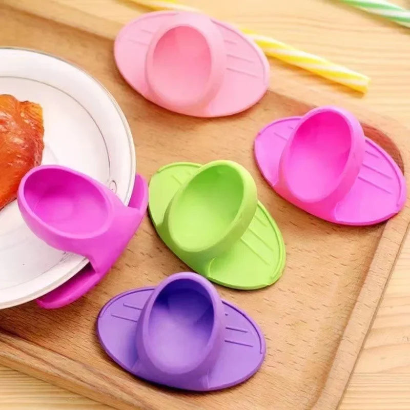 A collection of colorful silicone oven mitts and silicone spatulas are arranged on a wooden cutting board.