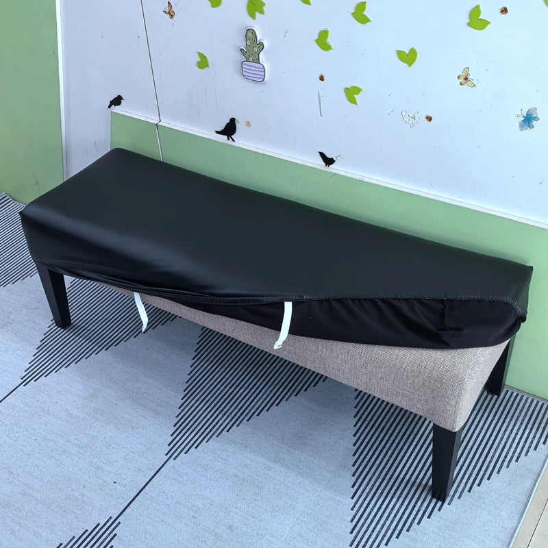 A black stretch pu leather waterproof bench slipcover placed on a light gray floor.