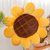 A yellow sunflower shaped throw pillow with a brown center is being held by a person.