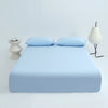 Light blue ice silk cooling fitted bed sheets set displayed on a bed with matching pillows and a lamp.