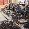 A black and gold floral print elastic sofa protective cover displayed on a light-colored sofa.