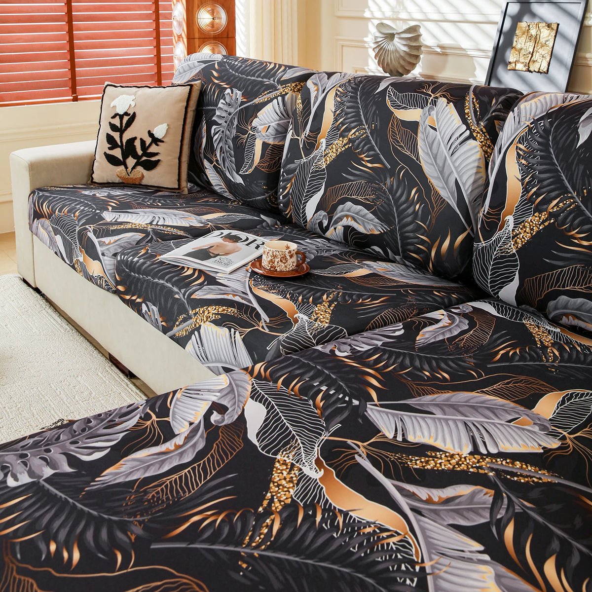 A black and gold floral print elastic sofa protective cover displayed on a light-colored sofa.
