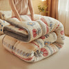 A fluffy, round winter blanket made of lamb'swool in cream and floral patterns is being held by a person.