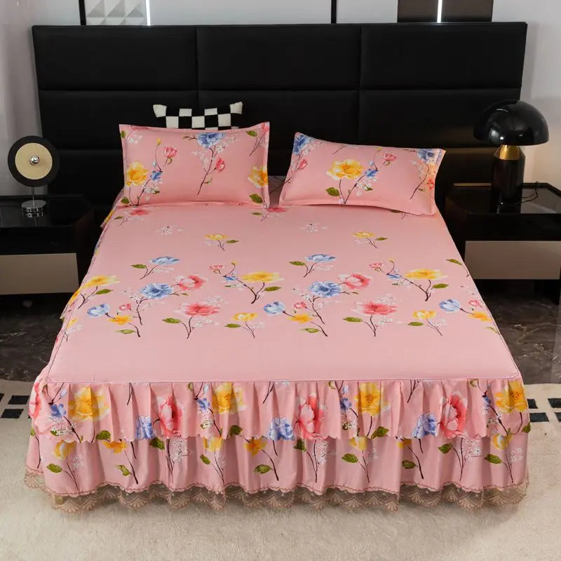 Pink floral bed skirt with pink pillows on a black headboard and dark nightstands.