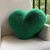 A vibrant green plush heart-shaped fox fur throw pillow resting on a light-colored sofa.