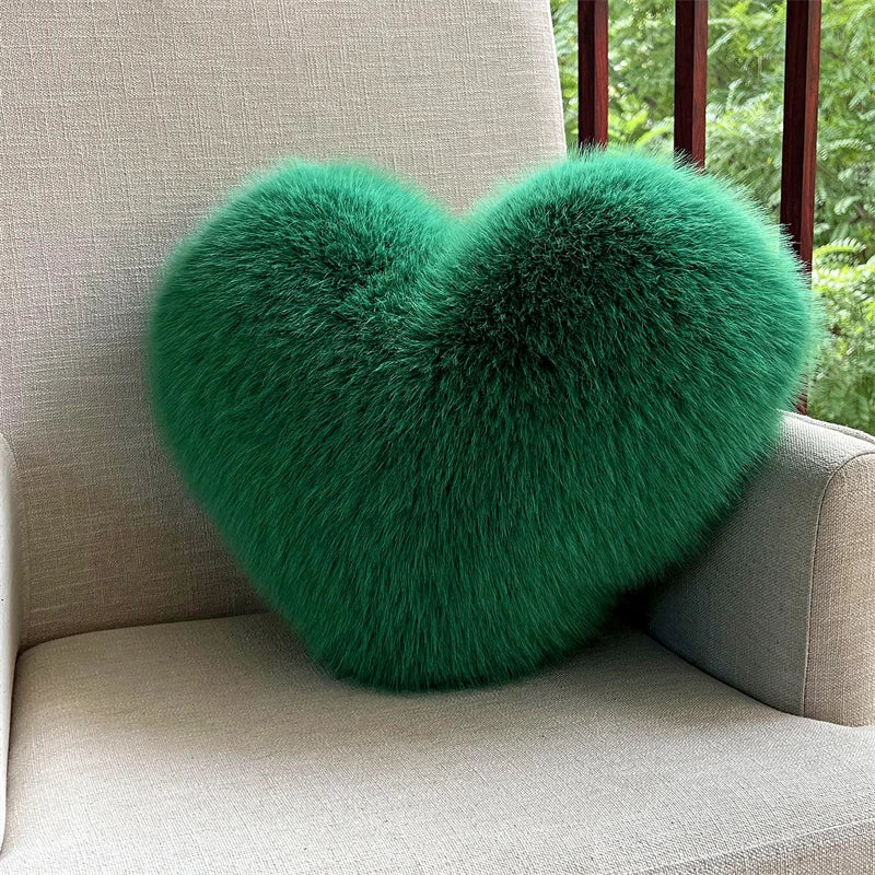 A vibrant green plush heart-shaped fox fur throw pillow resting on a light-colored sofa.