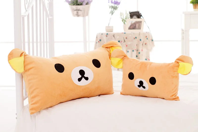 An orange Rilakkuma plush bed pillow and sofa cushion resting on a white surface.