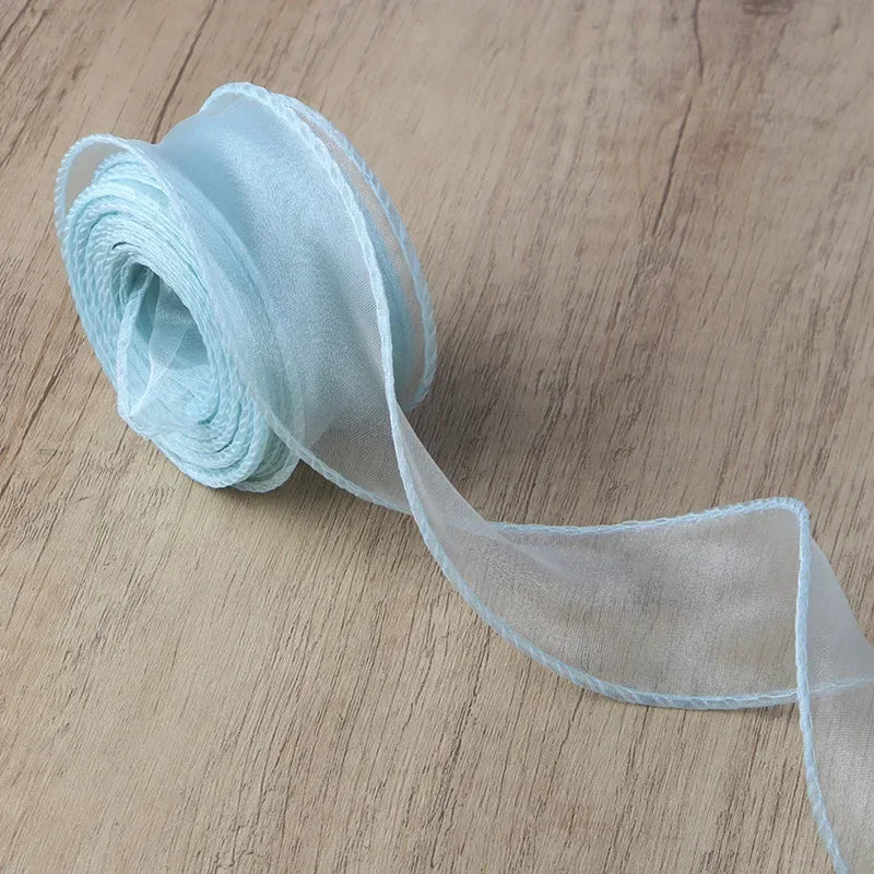 Light blue wavy edge organza ribbon rolled and unwound on a wooden surface