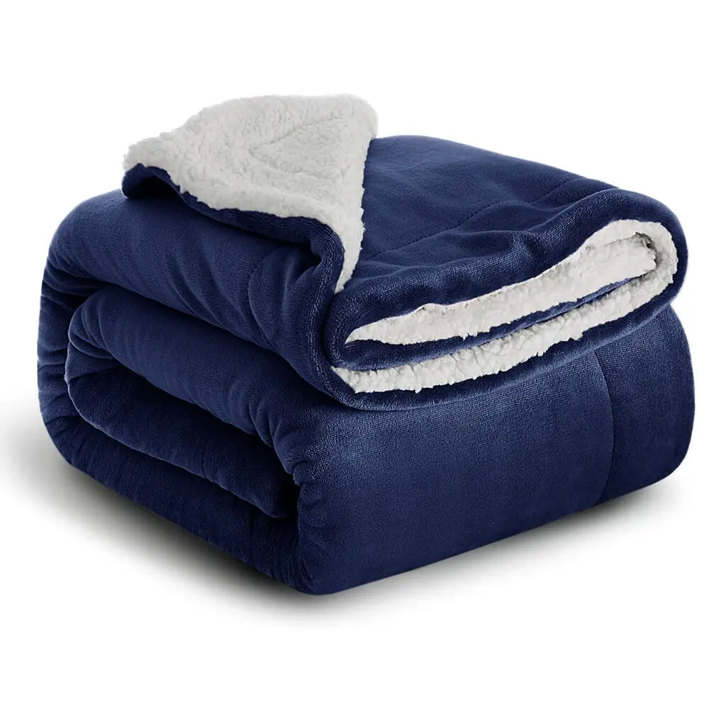 A dark blue sherpa fleece blanket folded and rolled, showing a white fluffy trim.