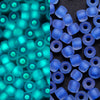 A close-up view of blue and cyan glow-in-the-dark glass seed beads in various sizes.