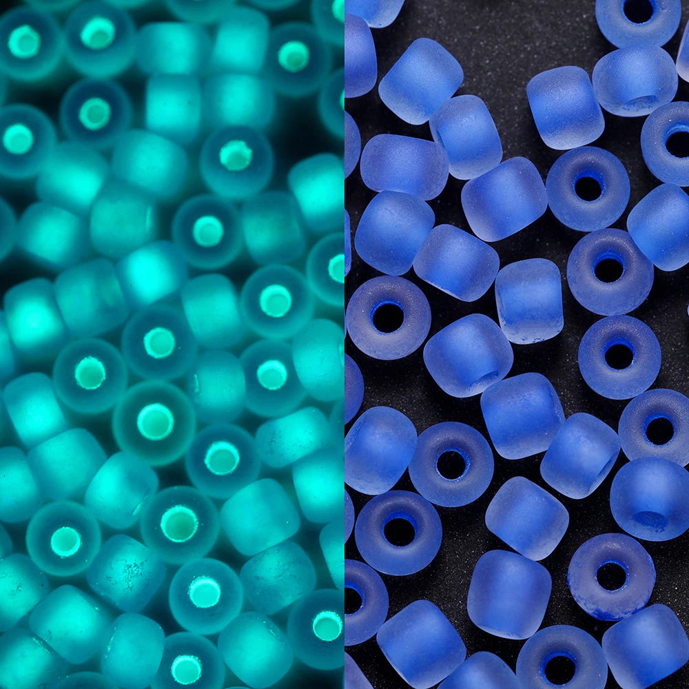 A close-up view of blue and cyan glow-in-the-dark glass seed beads in various sizes.