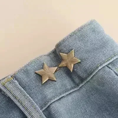A close-up of a denim jean cuff featuring an adjustable metal star brooch pin.