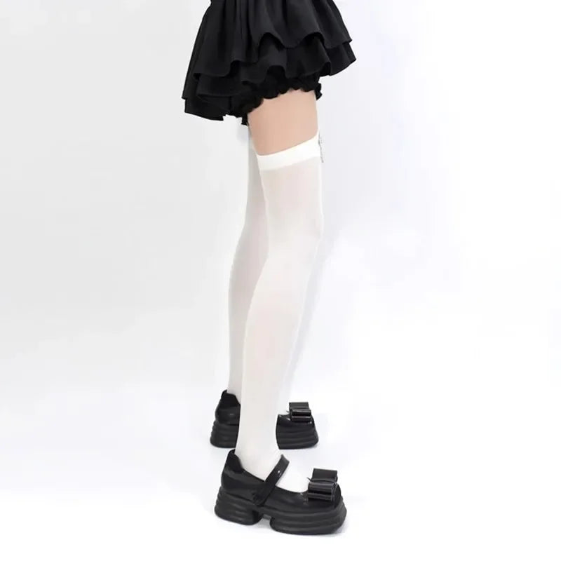 A pair of black ruffled fabric and white suspender socks worn by a person.