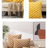 A collection of decorative plush pillow covers in yellow and beige textures displayed on a sofa.