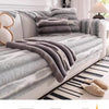 A gray striped anti-slip plush sofa cover draped over a light-colored sofa.