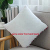 A white plush decorative pillow with a pink trim is shown resting on a light gray sofa.