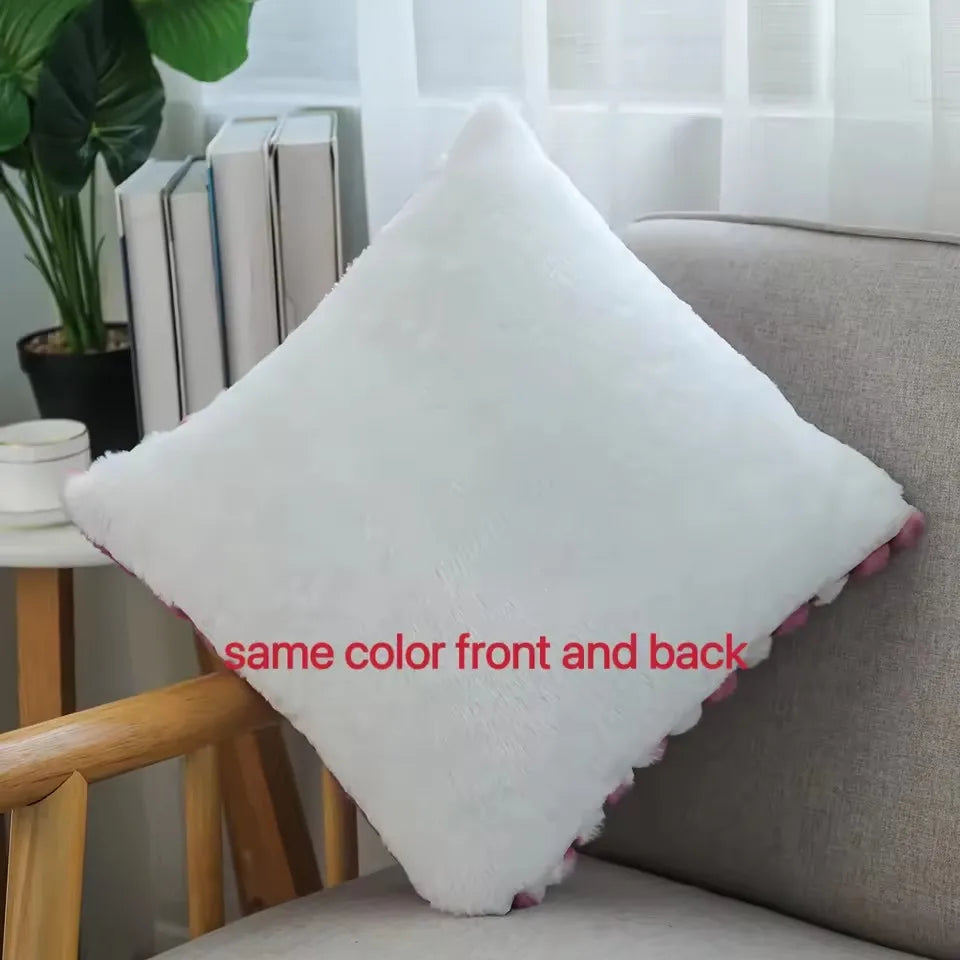 A white plush decorative pillow with a pink trim is shown resting on a light gray sofa.