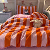 A pink and orange striped duvet cover set with a stuffed animal on a bed.