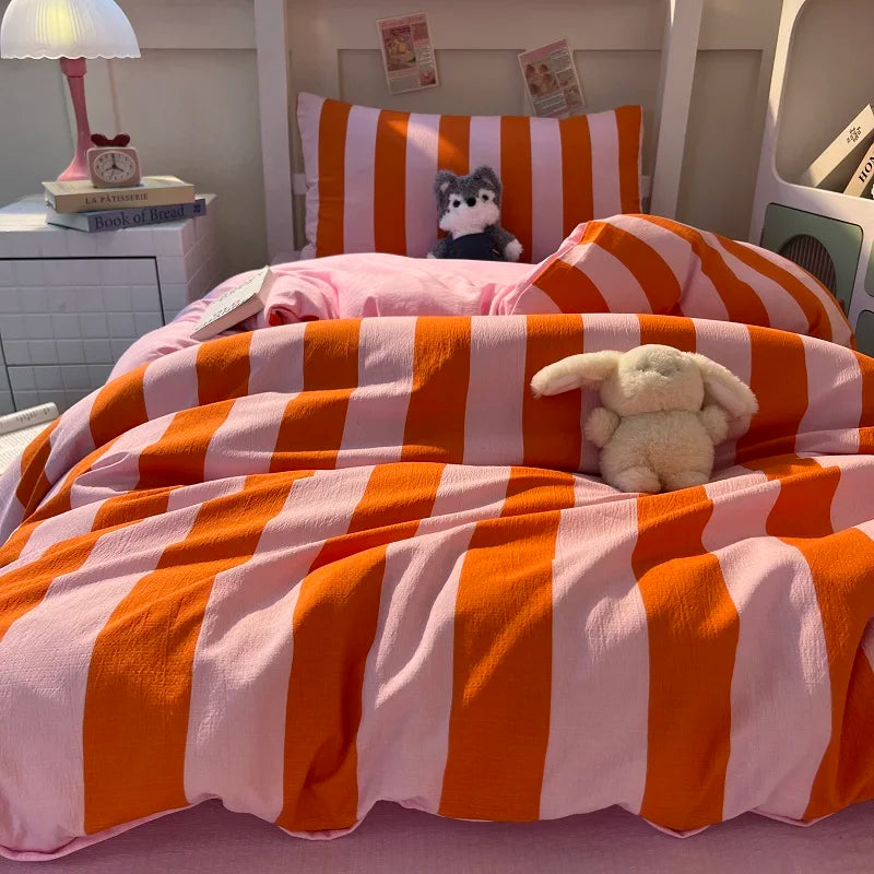 A pink and orange striped duvet cover set with a stuffed animal on a bed.