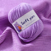 Purple soft yarn skein with a tag lying on a purple knitted fabric.