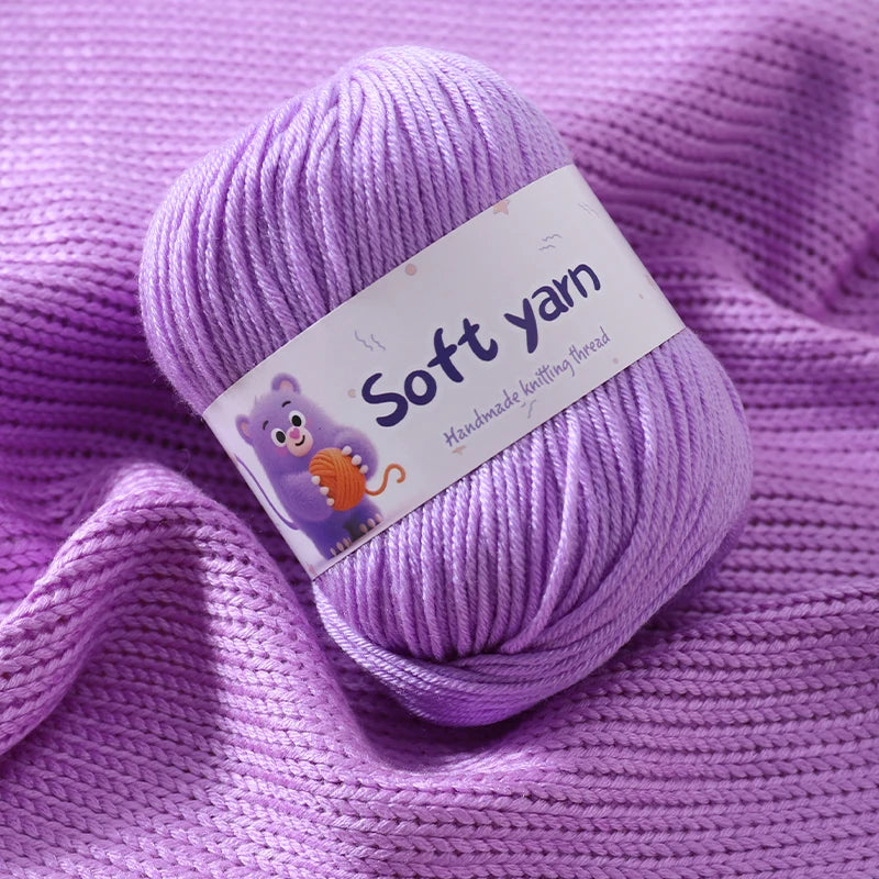 Purple soft yarn skein with a tag lying on a purple knitted fabric.
