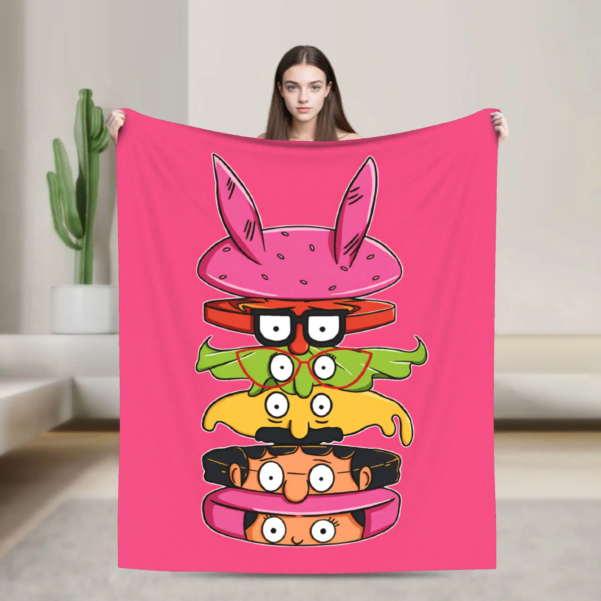 A pink throw blanket featuring a cartoon illustration of a character with large ears and expressive eyes.