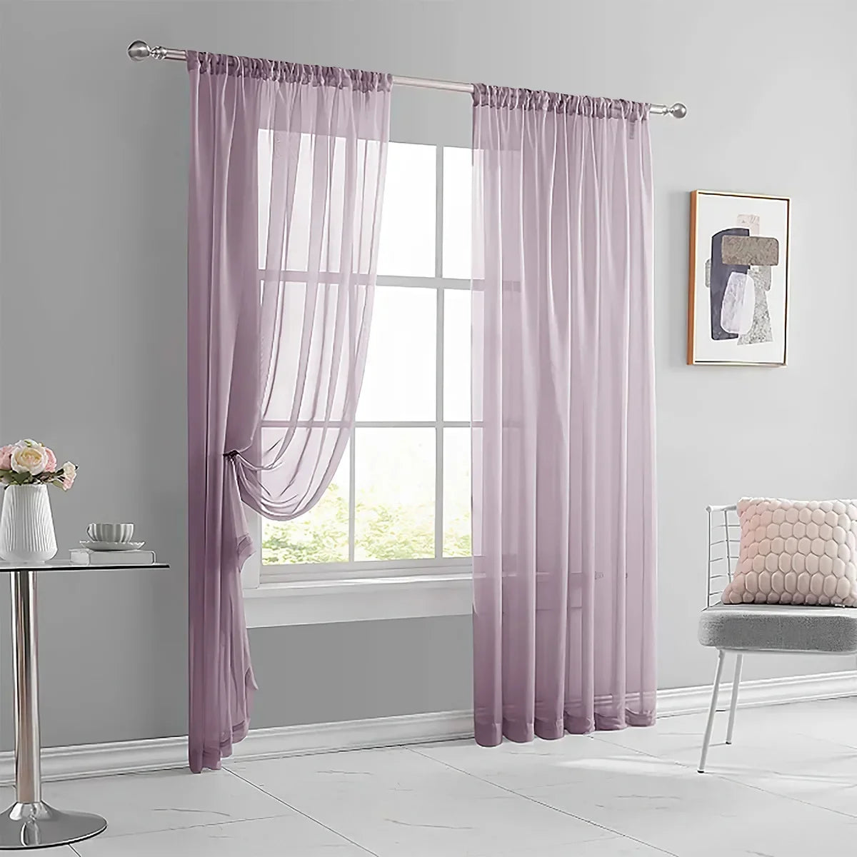 A pair of sheer lavender curtains hanging on a rod in a bright room.