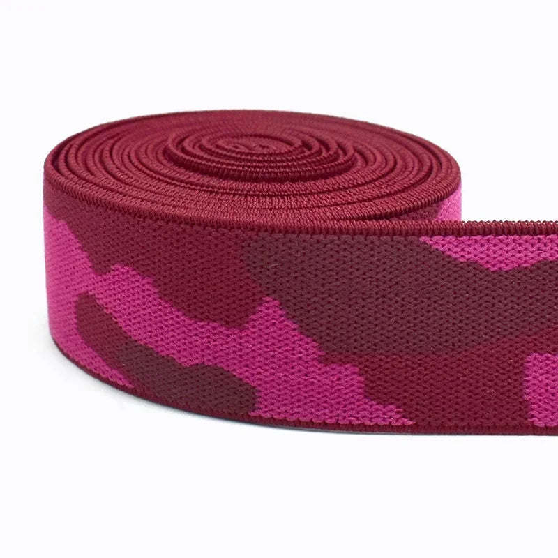 A roll of magenta camouflage elastic stretch ribbon for sewing and craft projects.