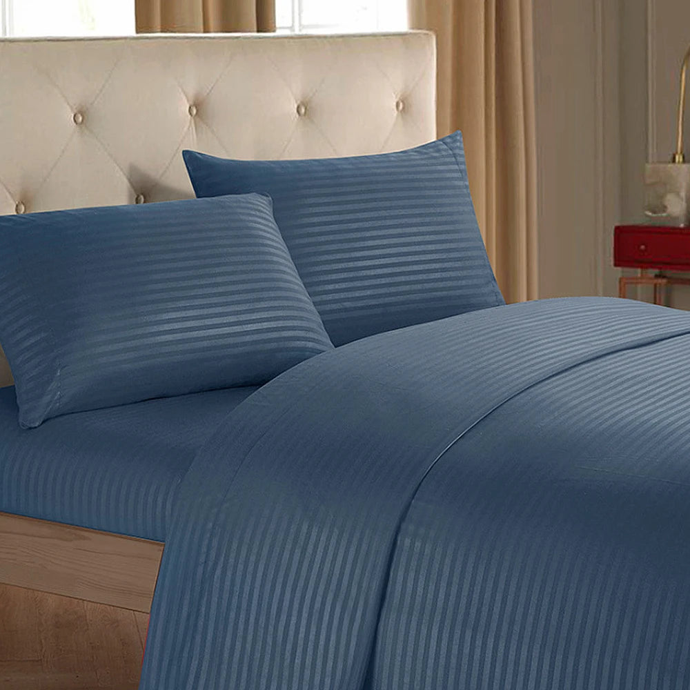 A close-up of a blue striped bedding set featuring a headboard and pillows in a bedroom setting.