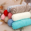 A collection of various colored and textured yarn skeins, including red, pink, gray, beige, and turquoise, arranged on a ligh