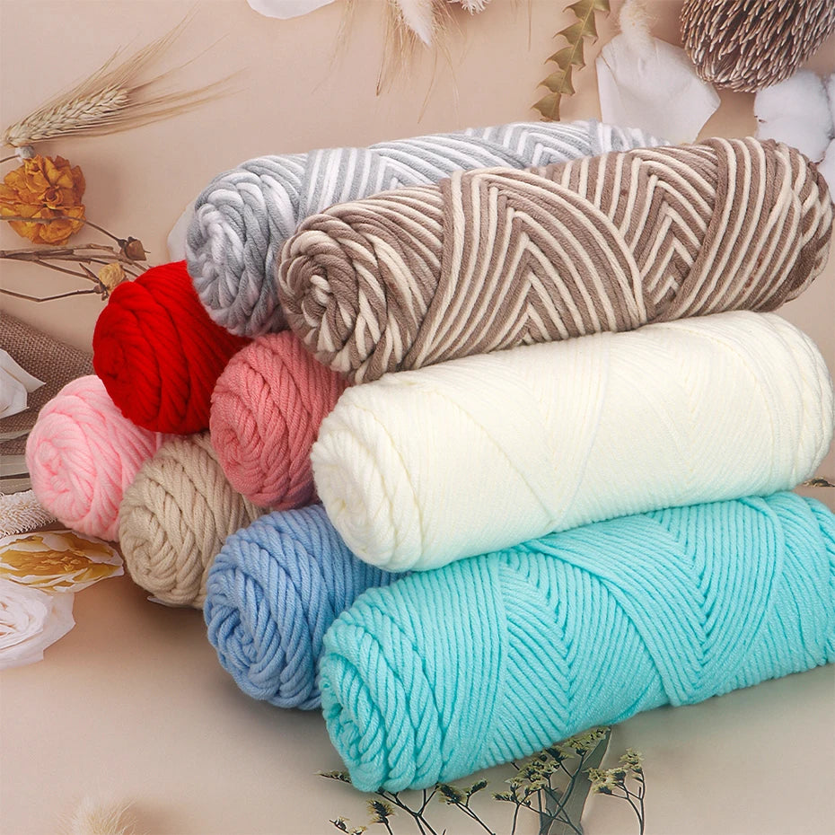 A collection of various colored and textured yarn skeins, including red, pink, gray, beige, and turquoise, arranged on a ligh