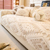 A beige boho jacquard fleece sofa slipcover with patterned cushions and a decorative spherical pillow.