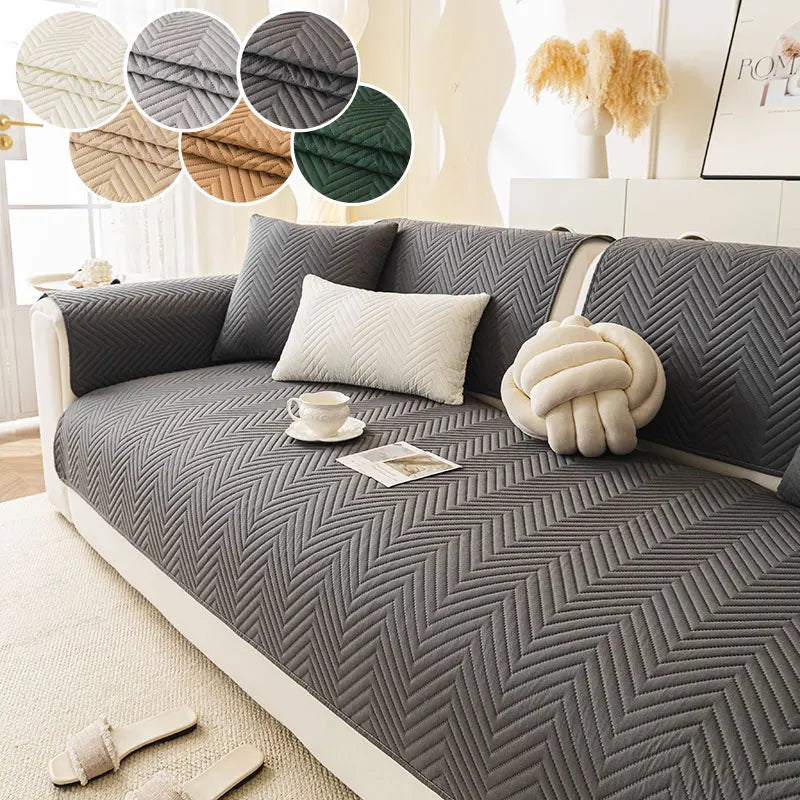 A gray anti-slip fabric sofa cushion cover with a chevron pattern and decorative pillows on a light-colored sofa.