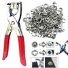 A set of metal sewing buttons and snap fasteners, including pliers and various button types.